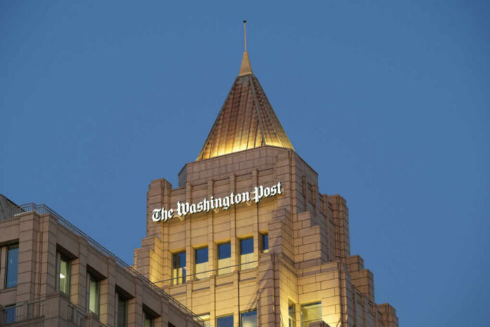 The top of a building featuring the sign of The Washington Post against a blue evening sky
