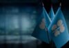 Three blue flags with a silver emblem on a blurred background