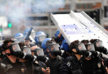 Leadership Clash SPARKS Violent Police Raid Riot police in gas masks with shields amid smoke