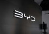 Illuminated BYD logo on a dark wall