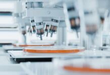 Ebola DECLARED Global Threat—Are Lockdowns Next? Automated laboratory equipment with robotic arms dispensing liquids into petri dishes