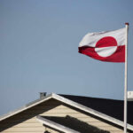 Flag of Greenland waving in the wind above a house