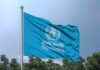 WHO Panic Button Slammed — Help Delayed! Flag of the World Health Organization waving against a blue sky