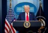 ALARM Bells Ring as Trump Stages Fed Ceremony A political figure at a podium during a press conference in front of the White House