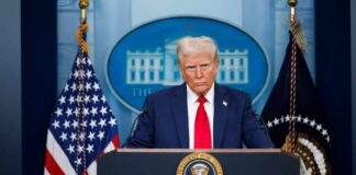 A political figure at a podium during a press conference in front of the White House