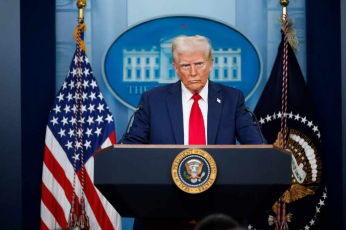 A political figure at a podium during a press conference in front of the White House