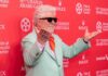 Man in mint green suit with orange tie poses on red carpet