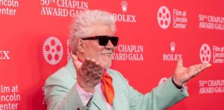 Man in mint green suit with orange tie poses on red carpet