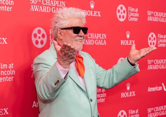 Man in mint green suit with orange tie poses on red carpet