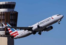 An American Airlines airplane taking off near an airport control tower