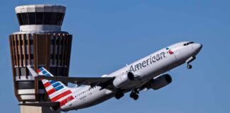 An American Airlines airplane taking off near an airport control tower