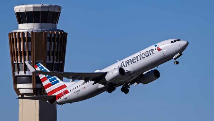 An American Airlines airplane taking off near an airport control tower
