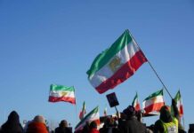 Tehran’s Chilling Threat: Reach Far Beyond Middle East Crowd holding Iranian flags during a protest against the government