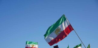 Tehran’s Chilling Threat: Reach Far Beyond Middle East Crowd holding Iranian flags during a protest against the government