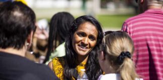 A woman in a yellow patterned top engaging in conversation with two other individuals outdoors