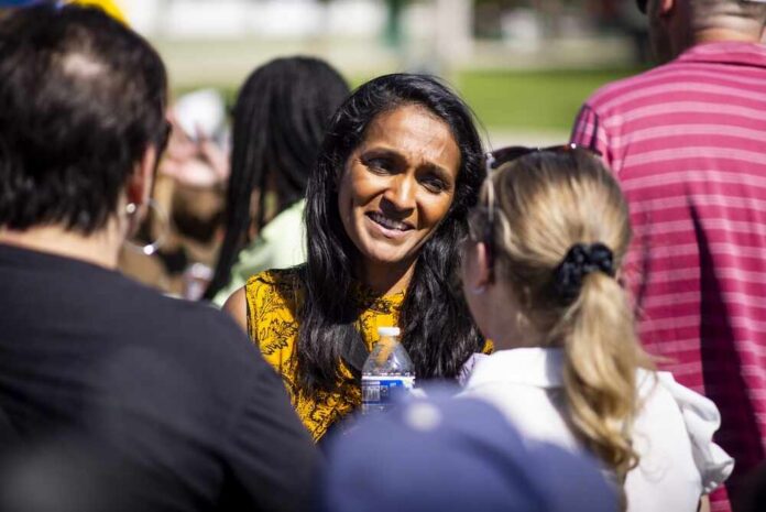 A woman in a yellow patterned top engaging in conversation with two other individuals outdoors