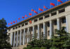 Trump in Beijing: Trade War Showdown Begins Facade of a government building adorned with red flags and a national emblem