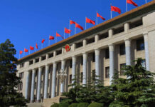 Facade of a government building adorned with red flags and a national emblem