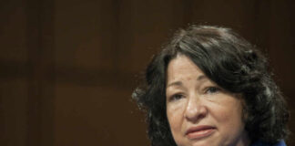 A woman in a blue blazer speaking during a formal hearing