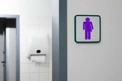 2144185979 Unisex restroom sign on a white wall