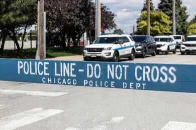 Yellow police caution tape at a crime scene with blurred figures in the background