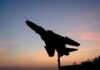 Silhouette of a fighter jet mounted on a pedestal at sunset