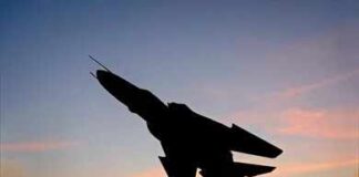 Silhouette of a fighter jet mounted on a pedestal at sunset