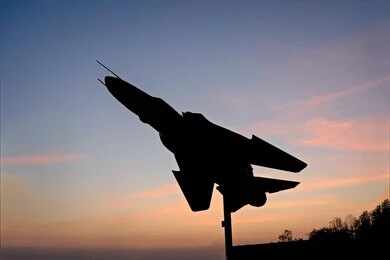 Silhouette of a fighter jet mounted on a pedestal at sunset