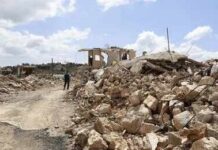Strikes Hit, Trust Craters In Lebanon Person walking past rubble and destroyed buildings on a dirt road