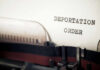 Close-up of a typewriter with a paper showing the words DEPORTATION ORDER