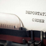 Close-up of a typewriter with a paper showing the words DEPORTATION ORDER