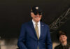 Biden Delivers Sharp Attack On Trump A smiling man in a suit and sunglasses at a military event, with a woman in uniform beside him