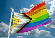 Rainbow Branding Backfires — Hypocrisy Exposed A colorful pride flag waving against a blue sky with clouds