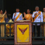 Group on palace balcony in formal attire waving