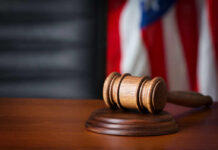 Light Rail Killing — Justice Stuck Again? A wooden gavel resting on a round base with a blurred American flag in the background