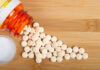 Pandemic Panic Fueling Risky Drug Hoards Spilled white pills from a prescription bottle on a wooden surface