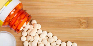 Pandemic Panic Fueling Risky Drug Hoards Spilled white pills from a prescription bottle on a wooden surface