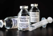 New AI Vaccine Raises Fresh Concerns Vials of COVID-19 vaccine and a syringe on a dark background