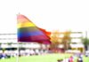 Women’s Sports Ruling Delivered Rainbow flag waving in the foreground with a blurred crowd in the background