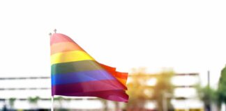 Women’s Sports Ruling Delivered Rainbow flag waving in the foreground with a blurred crowd in the background