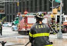 Firefighter in FDNY uniform overseeing emergency response at a city intersection