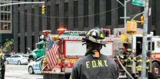 Firefighter in FDNY uniform overseeing emergency response at a city intersection