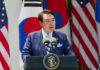 Court Sentences Former President To Prison A government official delivering a speech at a podium with flags in the background