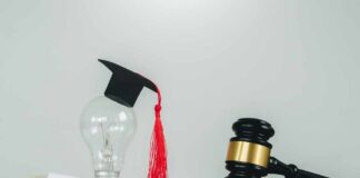 Light bulb with graduation cap beside open law book and judge’s gavel