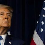 A political figure looking upward beside an American flag
