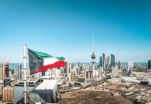 Kuwait flag waving over a city skyline with modern buildings