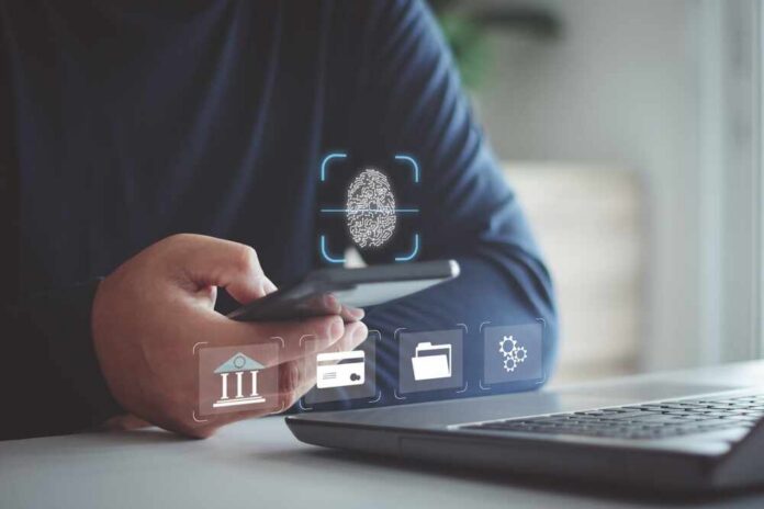 Biometric,Security,System.,Authentication,By,Fingerprint,Scan,Concept.,Digital,Connection, Person holding smartphone with fingerprint authentication near laptop