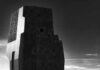 A modern architectural structure in black and white against a cloudy sky