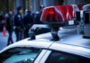 Close-up of a police car with red lights and officers in the background