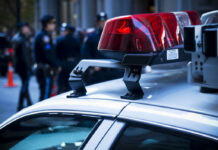 Close-up of a police car with red lights and officers in the background